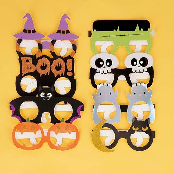 Set di occhiali in cartoncino Legami per feste di Halloween sovrapposti su uno sfondo giallo acceso